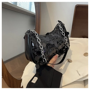 Détail d'un sac sous le bras à paillettes noires avec une grosse chaîne en métal argenté