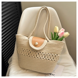 Detail of woven straw tote bag with brown leather flap and decorative oversized pearl button
