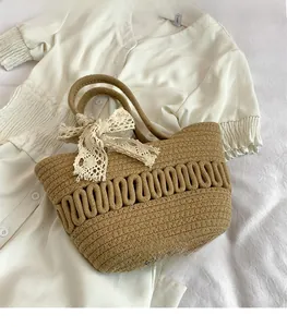 Détail du sac cabas en paille tissé à la main avec nœud en dentelle blanche et texture