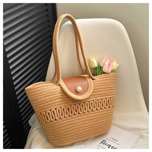 Detailed view of straw handbag featuring leather flap and oversized pearl buckle closure