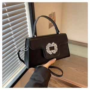 Détail d'un sac à main noir en similicuir avec boucle ronde en strass et garnitures argentées