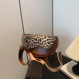 Detail of brown saddle bag with leopard print flap and wide textile shoulder strap