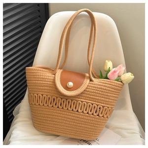 Detail of woven straw tote bag featuring brown faux leather flap and pearl button