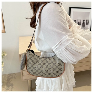 Détail du sac bandoulière tendance en forme de croissant avec motif trèfle et breloque