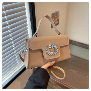 Détail d'un sac à main beige élégant avec une grande boucle carrée en strass et poignée