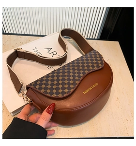 Detail of saddle bag featuring brown leather, vintage pattern, and gold metal hardware