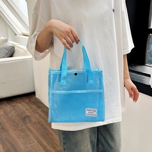 Light blue mesh tote bag for travel and beach use shown held by a model in a home setting