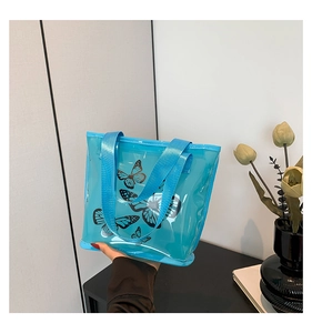Detailed view of blue transparent PVC tote bag with black butterfly pattern and woven handles