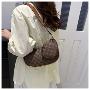Sac croissant à monogramme marron avec pochette ronde porté à l'épaule par un mannequin