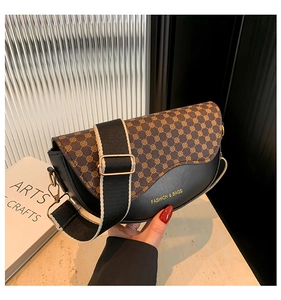 Detail of saddle bag with logo print, gold-tone hardware, and wide woven shoulder strap