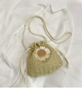 Close-up of straw bucket bag featuring intricate daisy weave and white cotton drawstrings