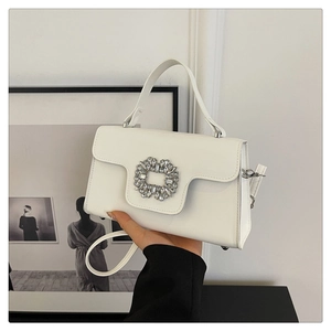 Détail du sac à main en cuir blanc avec boucle en cristal et bandoulière fine