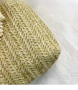 Close-up of woven straw bucket bag showing herringbone pattern and white floral accents