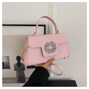 Détail d'un sac à main en cuir rose avec boucle carrée en cristal et bandoulière