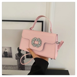 Gros plan du sac à main rose en cuir avec boucle en strass et fine bandoulière réglable