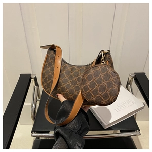 Détail de l'ensemble sac en croissant marron avec motif trèfle, pochette et bandoulière cuir