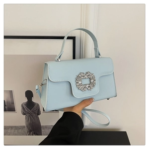 Détail d'un sac à main bleu clair avec une grande boucle décorative rectangulaire en strass
