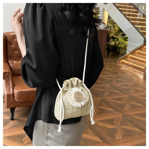 Close-up of handmade straw bucket bag with white daisy detail and drawstring strap
