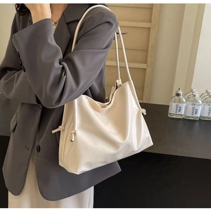 Détail d'un sac à bandoulière crème avec un nœud élégant sur le côté du sac à main
