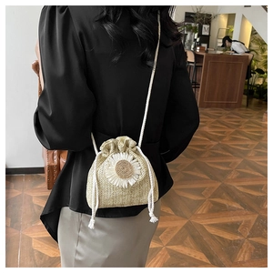 Detail of straw bucket bag with white daisy decoration and cotton shoulder strap