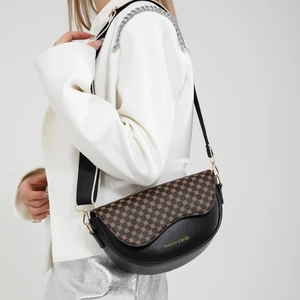 Black saddle bag with vintage pattern and wide fabric strap shown on a model