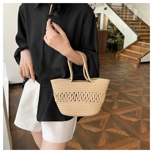 Détail du sac seau en paille à texture ondulée porté par un mannequin en intérieur
