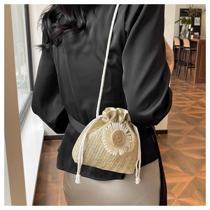 Detail of a straw woven bucket bag with daisy flower and drawstring cotton strap