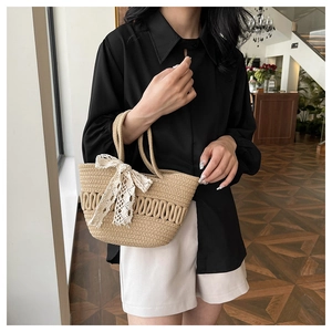 Détail du sac cabas tissé beige avec nœud en dentelle blanche et texture en paille