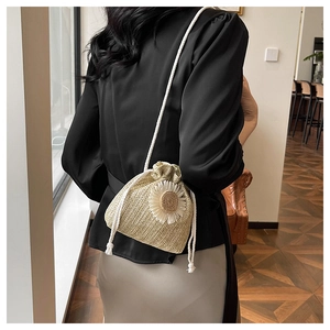 Detail of straw woven bucket bag with white daisy flower and cotton rope strap