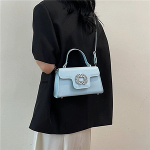 Petit sac carré bleu ciel avec boucle en cristal porté par un mannequin en blazer noir