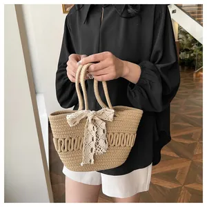 Détail du sac seau en paille tressée avec nœud en dentelle blanche et motif ondulé
