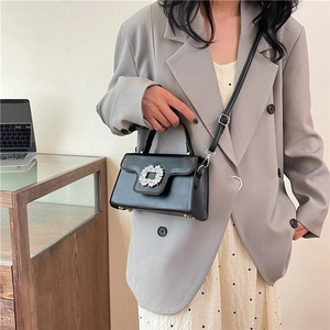 Sac à main chic en cuir noir orné d'une grande boucle argentée sertie de cristaux sur le rabat