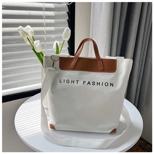 Detalle del bolso tote de lona blanca con ribete de cuero marrón y texto Light Fashion
