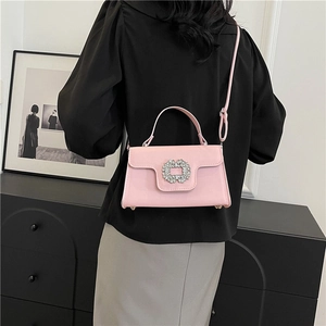 Sac carré rose avec boucle en strass porté par un mannequin pour l'effet de taille