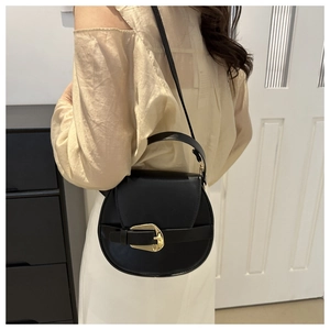 Nahaufnahme der schwarzen Satteltasche aus Leder mit goldener Schnalle an einem Model