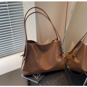 Détail du sac cabas en cuir caramel avec bretelles fines et nœuds décoratifs
