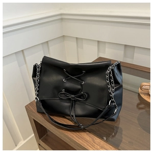 Detail of black crossbody bag featuring a chic bowknot and silver chain strap