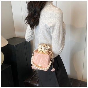 Chic pink drawstring bucket bag with pearl strap and golden chain detail on model