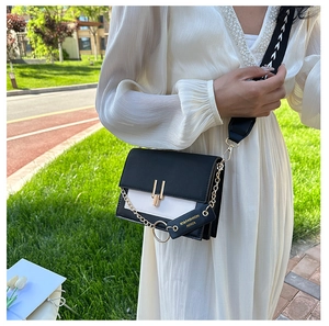 Detail of black and white leather crossbody bag with gold chain and printed strap