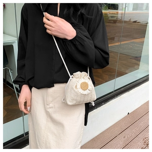 Detail of a mini straw bucket bag featuring a 3D daisy flower and drawstring closure