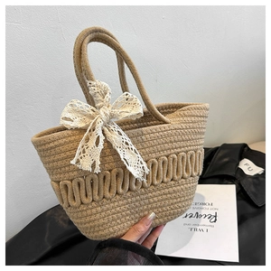 Détail du sac seau en paille tressée avec nœud en dentelle crème et texture fine