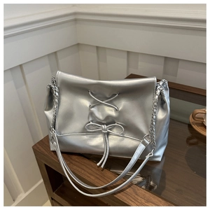 Detail of silver metallic tote bag featuring chic bow tie design and metal chain strap