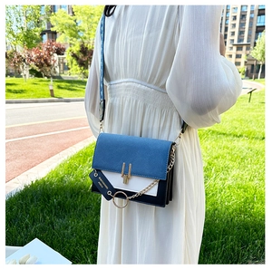 Detail of color-block crossbody bag with wide woven strap and large metal ring