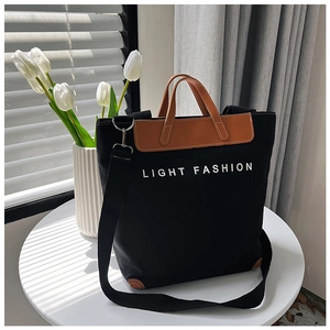Detalle de bolso tote de lona negra con ribetes de cuero marrón y logo Light Fashion