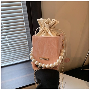 Pink drawstring bucket bag with textured faux leather and faux pearl handle detail