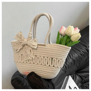 Détail macro du sac cabas tissé blanc cassé avec nœud en dentelle et motif vague