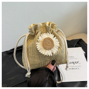 Detail of hand-woven straw bucket bag with white daisy flower and cotton drawstring