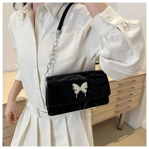 Close-up of black pleated shoulder bag with silver butterfly buckle and chain strap
