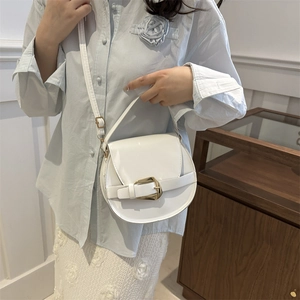 Modische weiße Satteltasche mit goldener Schnalle, getragen zum blauen Hemd