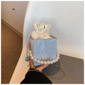 Detail of blue marble textured square bag with pearl handle and drawstring pouch